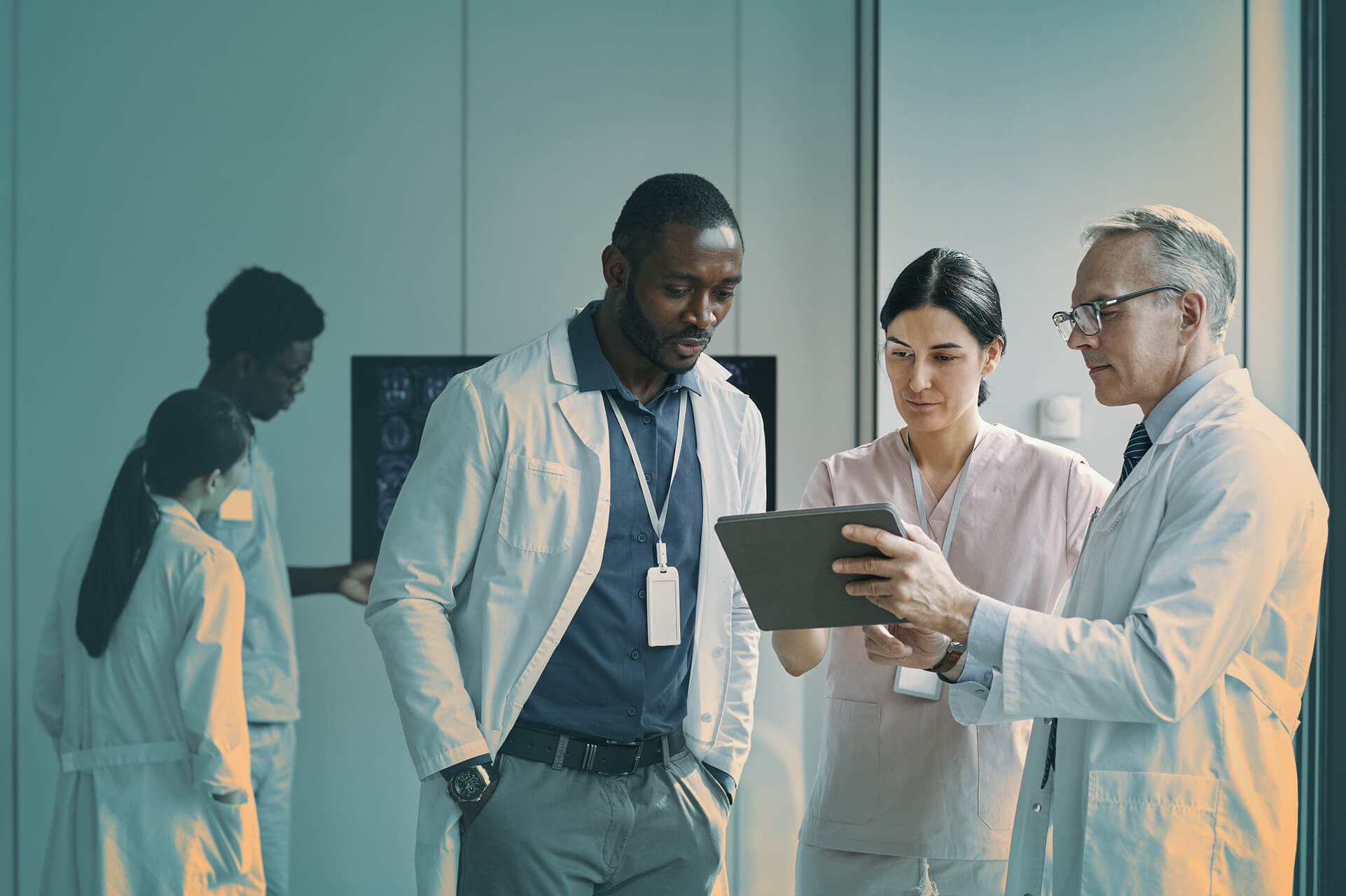 Medical professionals review digital data on a tablet during a healthcare cybersecurity discussion at a hospital.