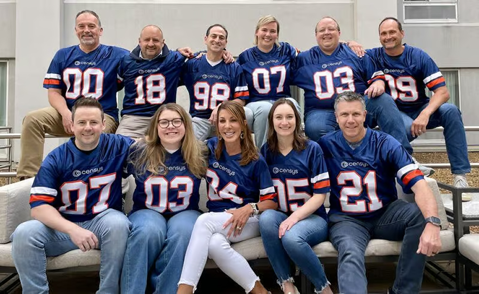 Censys team members wearing matching blue jerseys with numbers, posing outdoors on a sofa and steps.