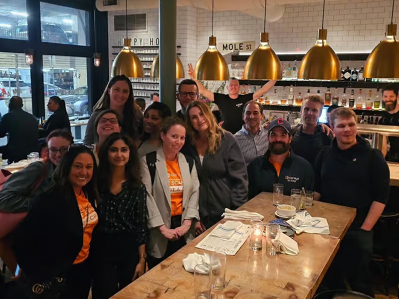 Group of Censys team members gathered around a table in a restaurant, smiling and celebrating together.
