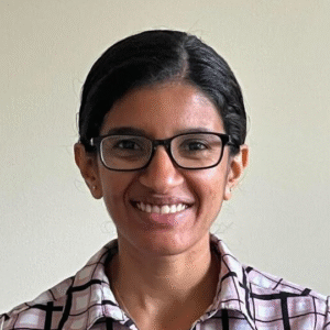 Censys Manasvini-Sethuraman smiling with glasses, wearing a checkered shirt against a plain background.