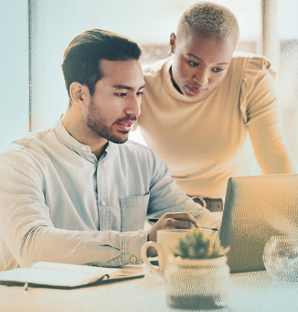 Two colleagues analyze data on a laptop, emphasizing clarity across their external attack surface.