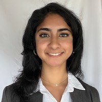 A young woman with long black hair, wearing a white shirt and black blazer, smiling confidently.